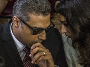 Al-Jazeera journalist, Canadian Mohamed Fahmy (L), accused along with Egyptian Baher Mohamed of supporting the blacklisted Muslim Brotherhood in their coverage for the Qatari-owned broadcaster, talks to human rights lawyer representing him, Amal Clooney (R), during their trial in the capital Cairo on August 29, 2015. The court sentenced Fahmy and Mohamed, along with Australian journalist Peter Greste who was tried in absentia after his deportation early this year, to three years in prison in a shock ruling following global demands for their acquittal. (AFP PHOTO / KHALED DESOUKI)