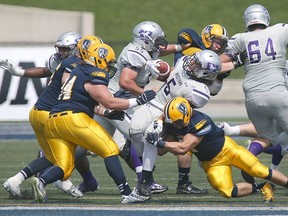 Western Mustangs running back Alex Taylor pushes for yards as Windsor?s Matt Gayer tries to take him down uring their OUA football season opener at Alumni Field in Windsor on Sunday. Western won 76-7. (DAX MELMER/The Windsor Star)