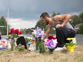 Fabio Melo plants flowers at a roadside memorial for friends Kayla DeMelo, 23, and Kyle Melo, 25, two Londoners killed on Friday night when the motorcycle they were riding crashed into a pickup truck, at the intersection of Ferguson Line and Wellington Road south of London, Ont. on Sunday August 30, 2015. (CRAIG GLOVER, The London Free Press)