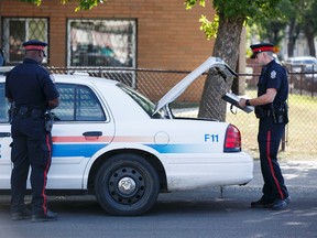Edmonton Police Service officers investigate after a body of man in his 20s was found lying in the street at 95 Street between 117 and 118 Avenue in Edmonton, Alta., on Monday August 31, 2015. Ian Kucerak/Edmonton Sun/Postmedia Network