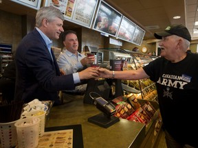 Prime Minister Stephen Harper and Leeds-Grenville MP Gord Brown serve coffee to Conservative supporters as Harper made a stop at a Tim Hortons in Gananoque on Monday. (THE CANADIAN PRESS/Adrian Wyld)