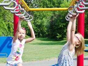 London Gibbs, 6, left, and Erica Stranc, 5, make their way across the bars at the Rogers Cove playground Monday, August 31, 2015. An active lifestyle for kids is part of Ontario’s The Healthy Kids Community Challenge. The city is participating in the program, which promotes health eating, physical activity and healthy lifestyle choices for children. Jessica Nyznik/ Peterborough Examiner/ Postmedia Network