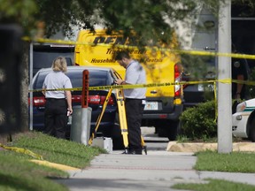 Law enforcement officials investigate the scene where an Orange County deputy shot a man who authorities say was stalking a female wrestler outside a World Wrestling Entertainment training facility, Monday, Aug. 31, 2015, in Orlando, Fla. The deputy had no choice but to shoot the man who he believed had a knife, Orange County Sheriff Jerry Deming said at a news conference. (AP Photo/John Raoux)