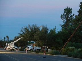 Power crews begin working on downed power lines to restore power to thousands left in the dark early on Tuesday, Sept. 1, 2015 in Phoenix, after monsoon storms hit the Phoenix area Monday night knocking out power to thousands, delaying air travel, and stranding motorists in flash floods. (AP Photo/Ross D. Franklin)