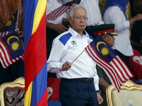 Malaysia's Prime Minister Najib Razak waves a Malaysian national flag during National Day celebrations in Kuala Lumpur, August 31, 2015. Malaysia's Independence Day celebrations took place on Monday, a day after thousands of protesters took part in the second day of a rally organised by pro-democracy group Bersih in Kuala Lumpur calling for electoral reform and Razak's resignation over a multi-million-dollar payment into an account under his name. REUTERS/Olivia Harris