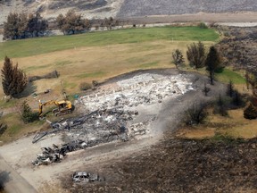 The remains of a structure lost to a wildfire days earlier are seen in this aerial view near still green fields Thursday, Aug. 27, 2015, near Chelan, Wash. The complex of fires burning throughout the area are the largest in state history. (AP Photo/Elaine Thompson)
