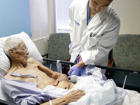 Plastic surgeon Anthony Echo, right, examines Frank Reyes' hand before surgery at Houston Methodist Hospital in Houston on Thursday, Aug. 27, 2015. Reyes, whose hand was badly burned, spent three weeks with his left hand surgically tucked under a pocket of tissue in his belly to give it time to heal and form a new blood supply. (AP Photo/Pat Sullivan)