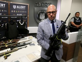 ALERT Insp. Darcy Strang holds one of the assault rifles that was seized along with seven other firearms, three body armour vests were seized and an estimated $125,000 worth of drugs in a joint investigation with Bonnyville RCMP. Tom Braid/Edmonton Sun/Postmedia