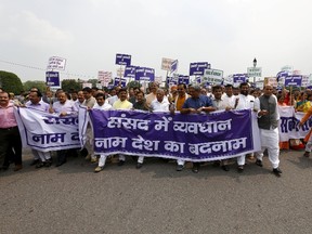 Lawmakers from India's ruling Bharatiya Janata Party (BJP) and its allies, take part in what they say is a "Save Democracy" march outside the parliament in New Delhi, India, August 13, 2015. The banner reads: "Obstruction in parliament, spoiling the country's name." Opposition parties, including the BJP, have recently staged more protests outside several government hospitals across Odisha, waving flags and shouting slogans against state government officials. (REUTERS/Adnan Abidi)