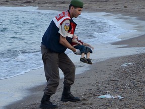 A Turkish gendarmerie carries a young migrant, who drowned in a failed attempt to sail to the Greek island of Kos, in the coastal town of Bodrum, Turkey, Sept. 2, 2015.  REUTERS/Nilufer Demir/DHA