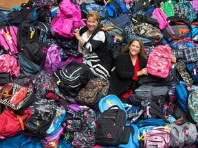 Supplies For Students program coordinators Natalie Trimble, left, and Chantal McLaughlin, right, lay among hundreds of school backpacks filled with school supplies destined for students in need at the Thames Valley District School Board headquarters on Dundas Street in London, Ont. on Thursday August 27, 2015. (CRAIG GLOVER, The London Free Press)