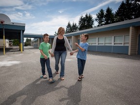 Twin eight-year-old brothers Taylor, left, and Riley Dalby walk with their mom Sharisse Dalby outside South Park School where they will enter Grade 3 this year, in Delta, B.C., on Monday August 24, 2015. THE CANADIAN PRESS/Darryl Dyck
