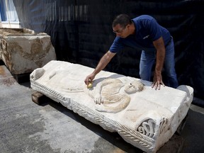 An employee of the Israel Antiquities Authority cleans an engraving on a sarcophagus as it is displayed for the media near the Israeli town of Beit Shemesh on Sept. 3, 2015. The Israel Antiquities Authority (IAA) said on Wednesday that their inspectors and Israeli policemen have revealed the rare sarcophagus after it was concealed by contractors, who damaged it when they incorrectly removed it from the ground and hid it during construction work in the southern city of Ashkelon. (REUTERS/Baz Ratner)