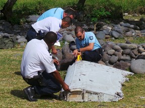 File picture shows French gendarmes and police inspecting a large piece of plane debris which was found on the beach in Saint-Andre, on the French Indian Ocean island of La Reunion, July 29, 2015. REUTERS/Zinfos974/Prisca Bigot/Files