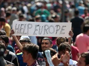 A man hold a placard reading "Help Europe" as Syrian and Afgan refugees attend a protest rally to demand to travel to Germany on September 2, 2015 outside the Keleti (East) railway station in Budapest. Hungarian authorities face mounting anger from thousands of migrants who are unable to board trains to western European countries after the main Budapest station was closed. 
AFP PHOTO / FERENC ISZA