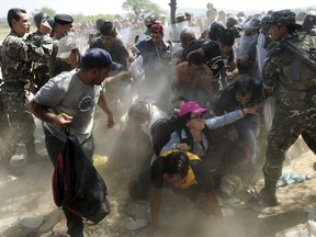 Migrants fall as they rush to cross into Macedonia after Macedonian police allowed a small group of people to pass through a passageway, as they try to regulate the flow of migrants at the Macedonian-Greek border September 2, 2015. Up to 3,000 migrants are expected to cross into Macedonia every day in the coming months, most of them refugees fleeing war, particularly from Syria, the United Nations said last week.  REUTERS/Ognen Teofilovski
