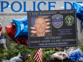 A memorial is in place at the Fox Lake Police Department on Wednesday, Sept. 2, 2015, in Fox Lake, Ill. for slain officer, Lt. Charles Joseph Gliniewicz. Gliniewicz was shot and killed Tuesday morning while pursuing a group of suspicious men. Authorities broadened the hunt Wednesday for three suspects wanted in the fatal shooting the popular Illinois police officer. (AP Photo/Nam Y. Huh)