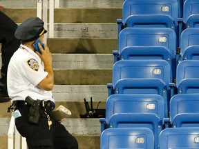 A police officer stands beside the remains of a drone that crashed into an empty section of seats at the U.S. Open in New York Thursday night. (AP Photo/Kathy Willens)