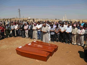 Syrian Kurds pray behind the coffins of the members of Kurdi family, two Syrian toddlers and their mother who drowned while they were trying to reach Greece, during a funeral ceremony in the northern border town of Kobani, Syria, September 4, 2015. Two Syrian toddlers who drowned with their mother as they were trying to reach Greece were laid to rest in the Syrian town of Kobani on Friday, a Reuters witness said. Abdullah Kurdi, their father, wept as their bodies were buried alongside each other in the "Martyrs' Ceremony" in the predominantly Kurdish town of Kobani, also known as Ayn al-Arab, near the border with Turkey. REUTERS/Herdem Dogrul