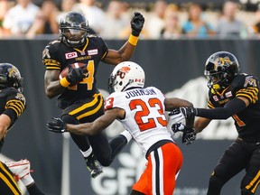 Tiger-Cats' Terrell Sinkfield Jr. (14) jumps towards Lions' Josh Johnson during CFL action in Hamilton on Aug. 15, 2015. (Mark Blinch/Reuters)