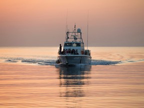 A coastguard boat with a group of migrants and refugees arrives at the port in the southeastern Greek island of Kos early Monday, Aug. 17, 2015. (AP Photo/Alexander Zemlianichenko)