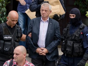Police officers escort the handcuffed mayor of Bucharest Sorin Oprescu from his house in Ciolpani, Romania, Sunday, Sept. 6, 2015. (AP Photo/Vadim Ghirda)