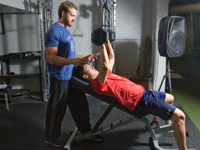 Strength and conditioning coach Mitch Stewart spots for London Knight Cliff Pu as he trains at Total Package Hockey training centre at Western Fair. (Derek Ruttan, The London Free Press)