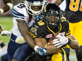 Hamilton Tiger-Cats' running back Anthony Woodson (18, right) is tackled by Toronto Argonauts' defensive back Akwasi Owusu-Ansah (9) during second-half CFL football action in Hamilton on Monday, August 3, 2015. The Hamilton Tiger Cats won the game 34-18. THE CANADIAN PRESS/Peter Power