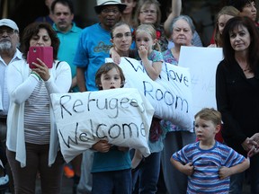 Melanie Richters, her son Ryan, 8, and daughter Sarah, 6, take part in a rally for Syrian refugees at City Hall on Sunday. (KEVIN KING/Winnipeg Sun)
