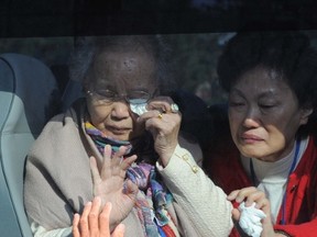 This photo taken on on November 5, 2010 shows South Korean Jung Soon-Ae (top L) and her daughter Choi Gyung-Ok (R) wave to their North Korean relative (bottom) as they bid farewell after a separated family reunion meeting at the Mount Kumgang resort on the North's southeastern coast, near the border.    AFP PHOTO/KOREA POOL/FILES