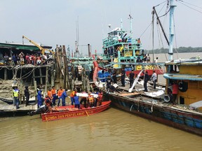 In this photo released by the Malaysian Maritime Enforcement Agency, a rescue team unload Friday, Sept. 3, 2015 a body of a victim retrieved from a search operation near the area where a boat carrying Indonesian migrants sank near Hutan Melintang, Perak state in Malaysia. (The Malaysian Maritime Enforcement Agency via AP)