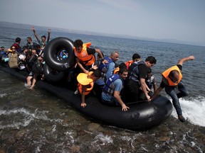 Syrian men, women and children arrive aboard a dinghy after crossing from Turkey, on the island of Lesbos, Greece, Monday, Sept. 7, 2015. (AP Photo/Petros Giannakouris)