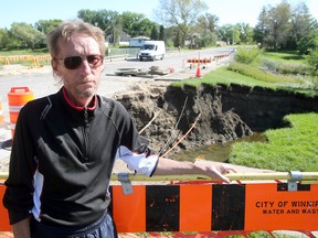 Brent Mackie stands by a large sinkhole open on Ness Avenue at Sturgeon Creek on Monday Sept. 07, 2015. The sinkhole opened during heavy rains last Friday.