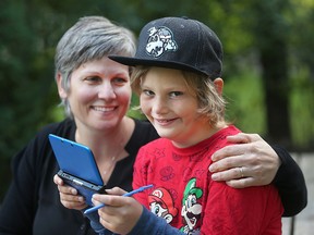 Carole Sparling (l) hugs her ten year old son Shea as he displays a Nintendo game in Winnipeg, Man. Tuesday Sept. 8, 2015. Shea received the game from the company president while on a trip from Dream Factory.