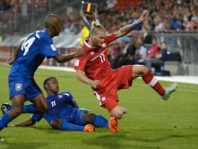 Team Canada's Mercel De Jong (right) fights for the ball against Belize's Jarret Davis (11) and Samuel Piette during the first leg of their World Cup qualifier in Toronto. (THE CANADIAN PRESS/Jon Blacker)