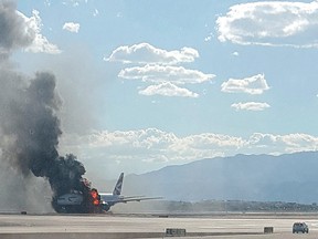 In this photo taken from the view of a plane window, smoke billows out from a plane that caught fire at McCarren International Airport in Las Vegas on Sept. 8, 2015. An engine on the British Airways plane caught fire before takeoff, forcing passengers to escape on emergency slides. (Eric Hays via AP)