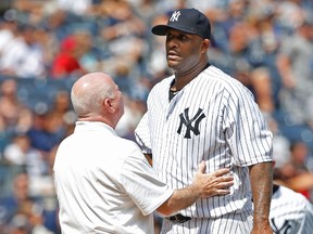 New York Yankees trainer Steve Donohue, left, talks to New York Yankees starting pitcher CC Sabathia on the mound in the third inning before New York Yankees manager Joe Girardi removed Sabathia from the baseball game against the Cleveland Indians at Yankee Stadium in New York, Sunday, Aug. 23, 2015. (AP Photo/Kathy Willens)