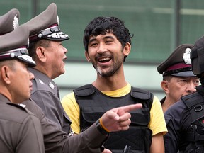 Police officers joke with a key suspect in last month's Bangkok bombing, yellow shirt, identified by Thai police as Yusufu Mierili, around a central Bangkok shopping centre during a reenactment for the Aug. 17 bombing at Bangkok's popular Erawan Shrine that left 20 people dead and more than 120 injured, Wednesday, Sept. 9, 2015. (AP Photo/Mark Baker)