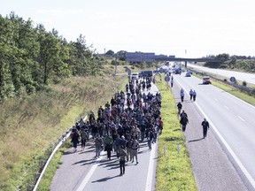 Around 300 migrants walk north on a highway escorted by police in southern Denmark on Wednesday, Sept. 9, 2015.  The migrants have crossed the border from Germany, and after staying at a local school, they say they are now making their way to Sweden, to seek asylum.  (Rune Aarestrup Pedersen/Polfoto via AP)