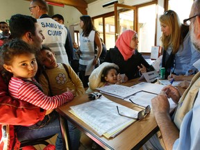 Refugees from Syria and Iraq speak with doctors for a medical check after they arrive at the Hubert Renaud centre in Cergy-Pontoise near Paris, France, Wednesday.  The group was the first among approximately 1,000 that French President Francois Hollande pledged to receive from the neighboring country Germany. JACKY NAEGELEN/AP PHOTO POOL
