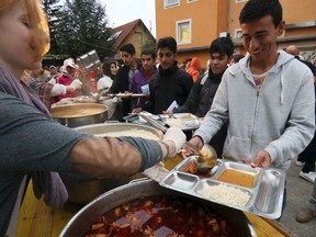 A man is offered food during Turkish born Aytekin Yilmazer's 37th birthday party at the refugee camp in Traiskirchen, Austria, Wednesday, Sept. 9, 2015. Yilmazer’s bash will be a night to remember _ both for him and the hundreds of refugees from Syria, Afghanistan and other troubled corners of the world who took up his invitation Wednesday to celebrate his 37th birthday. (AP Photo/Ronald Zak)