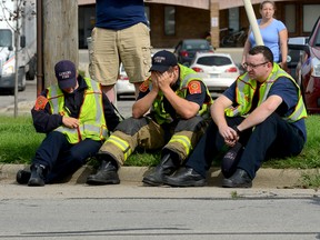 A firefighter puts his head in his hands as he and other firefighters sit on the curb on Cedar Street just north of Jolly Road Wednesday, Sept. 9, 2015 in Lansing, Mich. Dennis Rodeman, a 35-year-old Lansing firefighter has died after being struck by a hit-and-run driver as he collected money for charity. (Dave Wasinger/Lansing State Journal via AP)