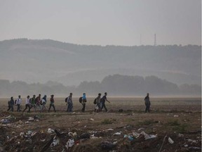 Syrian refugees walk through a field near the border town of Idomeni in northern Greece to cross into Macedonia in this file photo from early in 2015. SANTI PALACIOS / AP