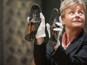 A Christie's employee holds running shoes worn by Sir Roger Bannister, which sold in the Out of the Ordinary auction at Christie’s London, Thursday Sept. 10, 2015.(Lauren Hurley/PA via AP)