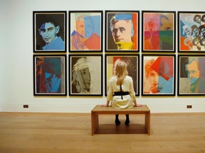 Gallery employee Maddy Adeane poses with Andy Warhol's "Ten Portraits of Jews of the Twentieth Century" (1980)  at the Dulwich Picture Gallery in London June 19, 2012.   REUTERS/Luke MacGregor