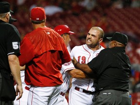 Cincinnati Reds first baseman Joey Votto (19) is restrained from getting to umpire Bill Welke (left) after being thrown out during the eighth inning Wednesday, Sept. 9, 2015, in Cincinnati. (AP Photo/John Minchillo)