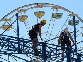 Workers finish assembling rides on the midway at the Western Fair grounds on Thursday. (MORRIS LAMONT, The London Free Press)