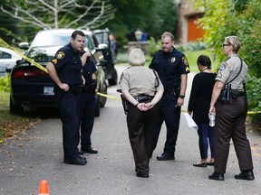 Police and deputies gather at the entrance to the road leading to a lakeside home where police said five family members, including three children, were found dead Thursday, Sept. 10, 2015 in Greenwood, Minn., an upscale western Minneapolis suburb in what police said appeared to be a murder-suicide. (AP Photo/Jim Mone)