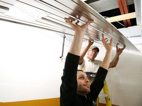 Richard Robillard, a maintenance worker, helps lead hand Mike Brosseau install a ceiling panel in a change room at the newly renovated Chelmsford Arena. Gino Donato/Sudbury Star/Postmedia Network