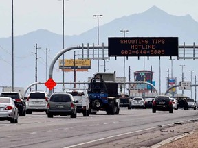 An Arizona Department of Transportation sign gives a hotline number for information on the recent freeway shootings as motorists pass under at the 202/I-10 intersection, Wednesday, Sept. 9, 2015 in Chandler, Ariz. Authorities are investigating nine shootings of vehicles over the past two weeks along I-10 in Phoenix. A truck's passenger window shattered on a Phoenix freeway Wednesday as Arizona authorities investigated a string of highway shootings that have rattled nerves and heightened fears of a possible serial shooter. (AP Photo/Matt York)